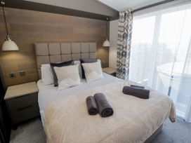 A bedroom with a bed and bedside table at Stone Crab Lodge in Haverfordwest