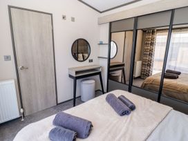 A bedroom with a bed and dresser at Stone Crab Lodge in Haverfordwest