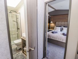 A bathroom with a shower and toilet adjacent to a bedroom at Stone Crab Lodge in Haverfordwest