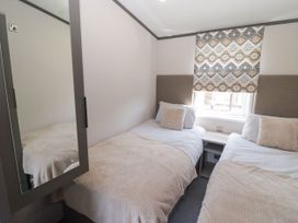 A bedroom with twin beds and a window at Stone Crab Lodge in Haverfordwest