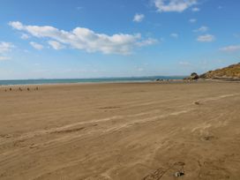 A beach with people walking and a dog at Stone Crab Lodge in Haverfordwest