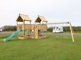 A playground structure with a slide and swings at Stone Crab Lodge in Haverfordwest