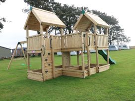 A play structure with a slide and climbing wall in an outdoor area at Stone Crab Lodge in Haverfordwest