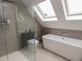 A bathroom with a shower, bathtub, toilet, and sink at Ty Hebog 