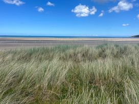 A beach with grass and sand along the shoreline at Ty Hebog Beaumaris