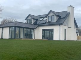 A house with a lawn and multiple windows at Ty Hebog in Beaumaris