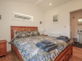 A bedroom with a bed and nightstand at Wisteria Lodge in Redruth