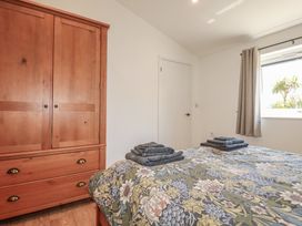 A bedroom with a wardrobe and bedding at Wisteria Lodge Redruth