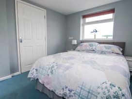 A bedroom with a bed, light and door at Likely Sunset in St. Austell