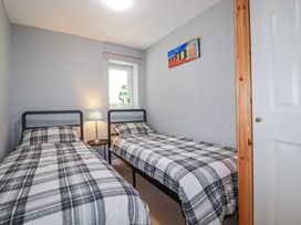 A bedroom with two single beds and a lamp at Likely Sunset in St. Austell