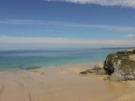 A beach with people and cliffs at Likely Sunset in Newquay