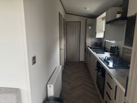 A kitchen with cabinets and appliances at Lochwood Platinum Superior at Three Lochs Holiday Park in Newton Stewart