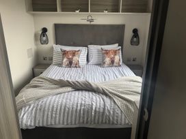 A bedroom with a bed and lamps at Lochwood Platinum Superior at Three Lochs Holiday Park, Newton Stewart