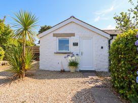 A cottage with a door and window surrounded by gravel and plants at Primrose Cottage Redruth