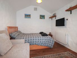 A bedroom with a bed, sofa, and television at Primrose Cottage in Redruth