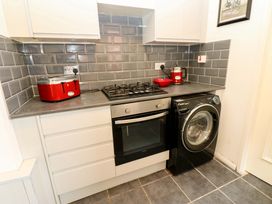 A kitchen with a gas stove, washing machine, and red kettle at 17 Fairfield Road