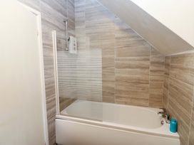 A bathroom with a bathtub and shower screen at 17 Fairfield Road