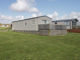 A mobile home with a fence and grass at Fanfare Superior at Three Lochs Holiday Park Newton Stewart