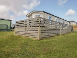 A caravan with a fence and grass area at Standard Caravan at Three Lochs Holiday Park Newton Stewart