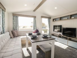 A living room with a dining table and sofa at Standard Caravan at Three Lochs Holiday Park in Newton Stewart