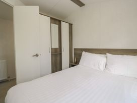 A bedroom with a bed and wardrobe at Standard Caravan at Three Lochs Holiday Park, Newton Stewart