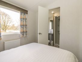 A bedroom with a bed and a bathroom view at Standard Caravan at Three Lochs Holiday Park Newton Stewart