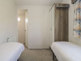 A bedroom with two beds and a wardrobe at Standard Caravan at Three Lochs Holiday Park, Newton Stewart