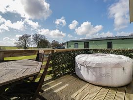 An outdoor area with a hot tub and seating at Standard Caravan at Three Lochs Holiday Park Newton Stewart