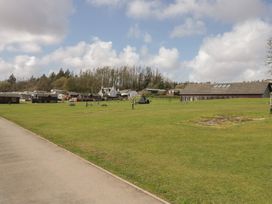 An outdoor area with grass, buildings, and picnic tables at Standard Caravan at Three Lochs Holiday Park, Newton Stewart