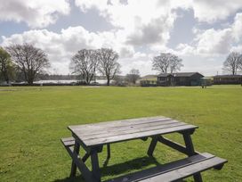 A picnic table on grass with trees and buildings in the background at Standard Caravan at Three Lochs Holiday Park Newton Stewart