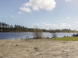 A lake with trees and a bench at Standard Caravan at Three Lochs Holiday Park in Newton Stewart