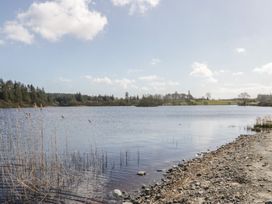 A lake with trees and rocks at Standard Caravan at Three Lochs Holiday Park Newton Stewart