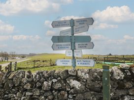 A signpost with various directions near a road at Standard Caravan at Three Lochs Holiday Park, Newton Stewart