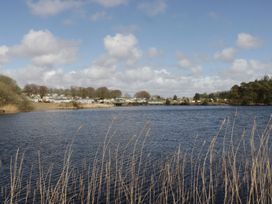 A view of a lake with caravans and trees at Lochwood Platinum Superior at Three Lochs Holiday Park Newton Stewart