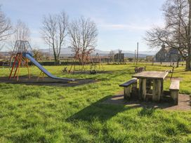 A playground with a slide, swing set, and a picnic table at 2 Bryn Eglwys in Prenteg