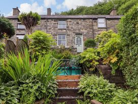 A garden with a stone house and plants at 2 Bryn Eglwys Prenteg