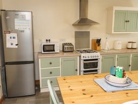 A kitchen with a fridge, stove, and dining table at 2 Bryn Eglwys Prenteg
