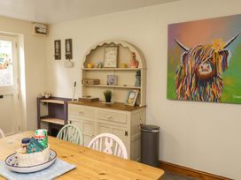 A dining room with a wooden table and a shelf holding decorative items at 2 Bryn Eglwys Prenteg