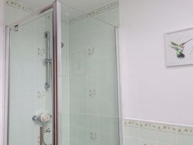 A shower with tiled walls and a bird painting at 2 Bryn Eglwys Prenteg
