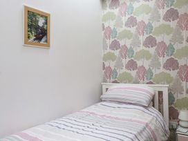 A small bedroom with a bed and a picture frame at 2 Bryn Eglwys in Prenteg