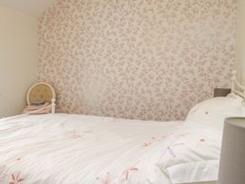 A bedroom with a bed and floral wallpaper at 2 Bryn Eglwys Prenteg