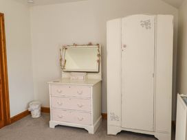 A bedroom featuring a dresser with a mirror and a wardrobe at 2 Bryn Eglwys in Prenteg