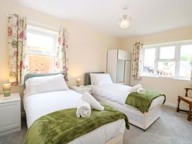 A bedroom with two beds and window light at The Mill House Gardens