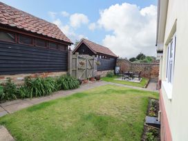 A garden with table and chairs surrounded by sheds at The Mill House Gardens