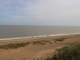 A beach with people walking along the shoreline at The Mill House Gardens