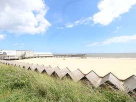 A beach with a pier and buildings at The Mill House Gardens in 