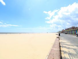 A beach scene with a boardwalk and colorful beach huts at The Mill House Gardens 