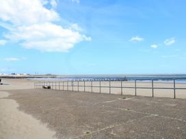 A beach view with sand, water, pier and railings at The Mill House Gardens 