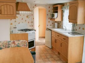 A kitchen with cabinets, stove, sink, and refrigerator at Number 186 Owens caravan park Abergele