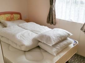A bedroom with a bed and pillows at Number 186 Owens caravan park in Abergele